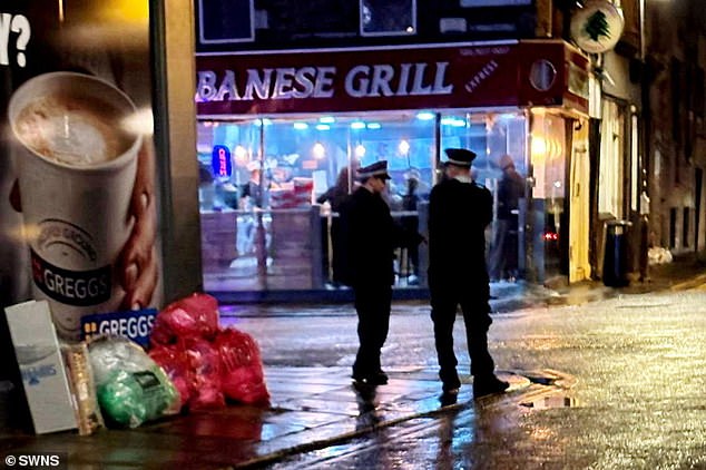 Two police officers are pictured on the streets outside the restaurant, where residents have reported loud noise, litter and fights, at night