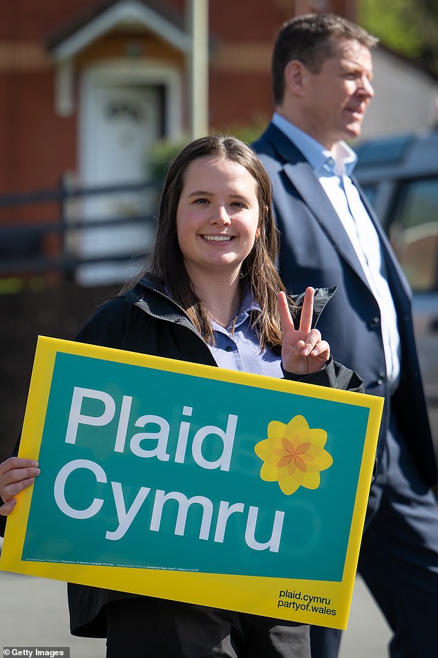 Zaynub Akbar, Plaid Cymru's candidate for Caerdydd Ffynnon Taf, holds a campaign sign in front of her party's leader Rhun ap Iorwerth