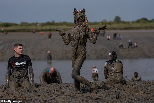 Runners become drenched in mud as they clamber over the drained river bed
