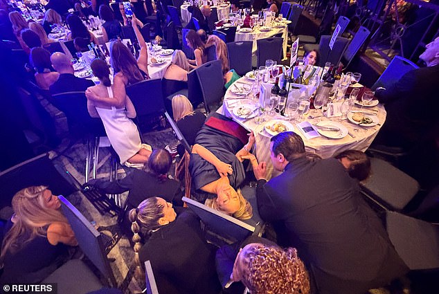 Guests take cover after U.S. President Donald Trump and first lady Melania Trump were rushed out of the White House Correspondents' Association dinner