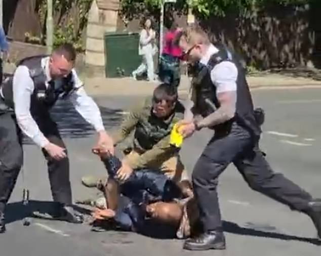 Officers kick the suspect in the head after Tasering him. They were helped by a passer-by (right)