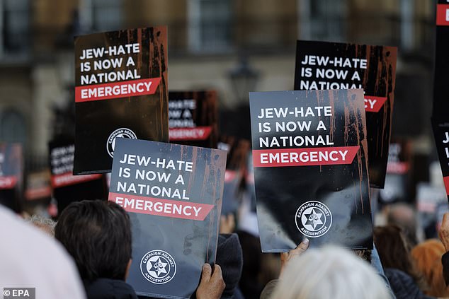 People hold up placards, which read 'Jew-hate is now a national emergency', during a protest organised by the Campaign Against Antisemitism outside Downing Street