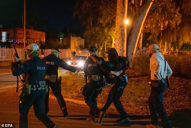 Heavily-armed police escorted an injured woman being carried away from the overnight riots in the streets of Alice Springs