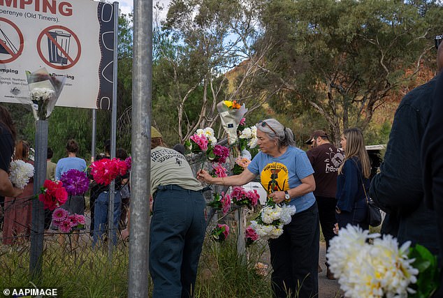 Locals place flowers on the fence at the camp where Kumanjayi Little Baby lived