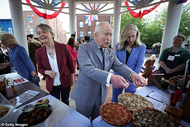 King Charles III, accompanied by Virginia Governor Abigail Spanberger (R) speaks with employees of Melting Pot Pizza during a parade and block party on the final day of the state visit