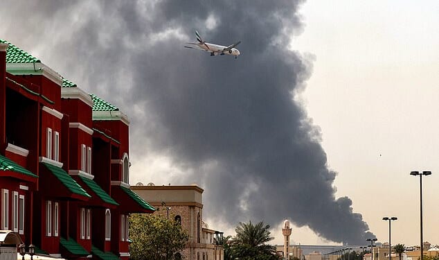 A plane flying through a plume of smoke after a fire broke out at Dubai International Airport