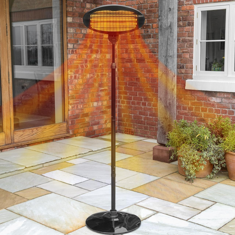 Outdoor patio heater illuminating a brick wall and paved patio.