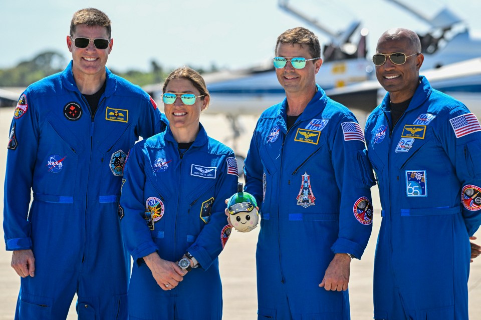 Artemis II astronauts Jeremy Hansen, Christina Koch, Reid Wiseman, and Victor Glover pose in their blue flight suits.