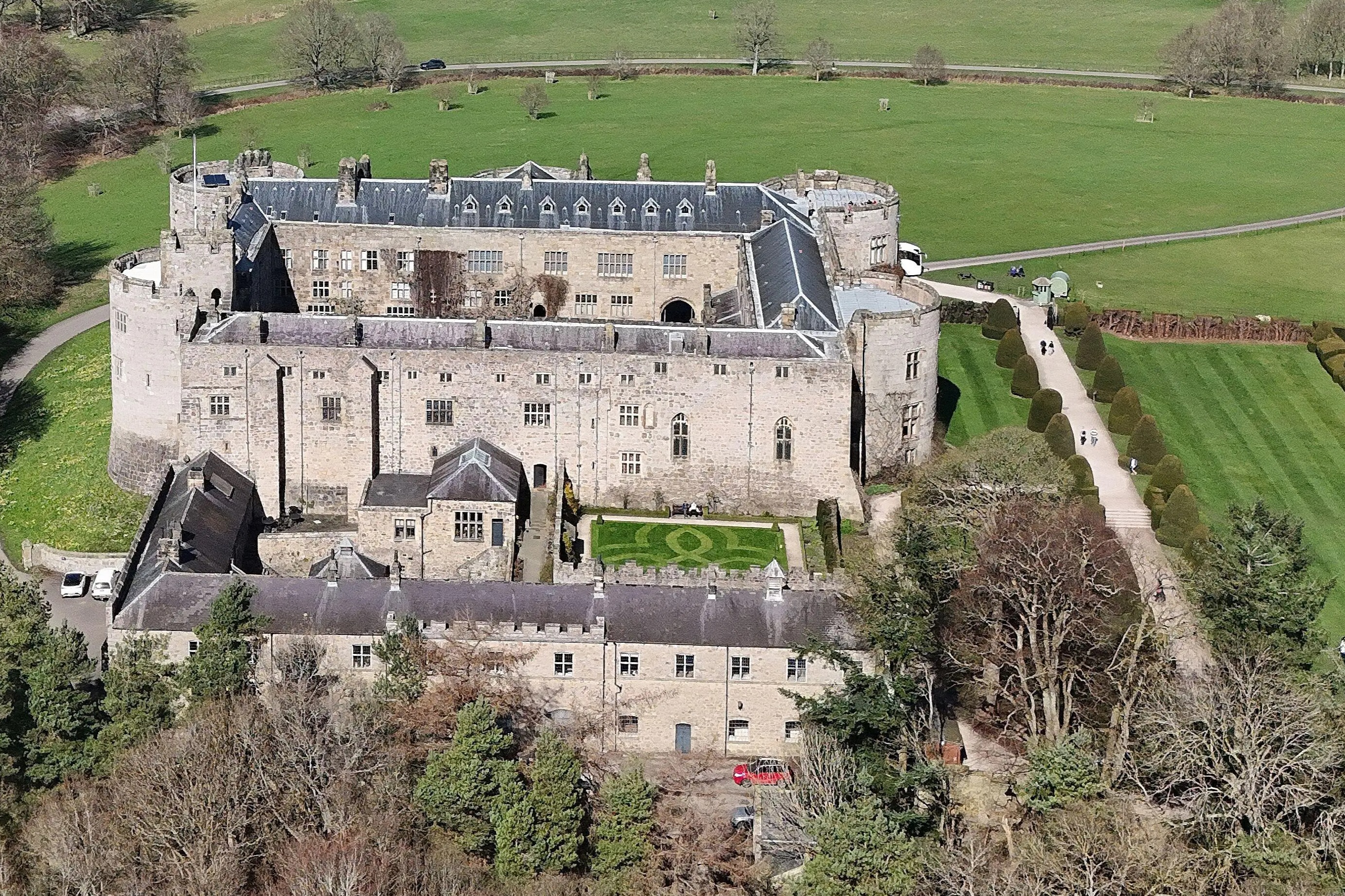 Aerial view of Chirk Castle and its gardens with surrounding fields and a lake.
