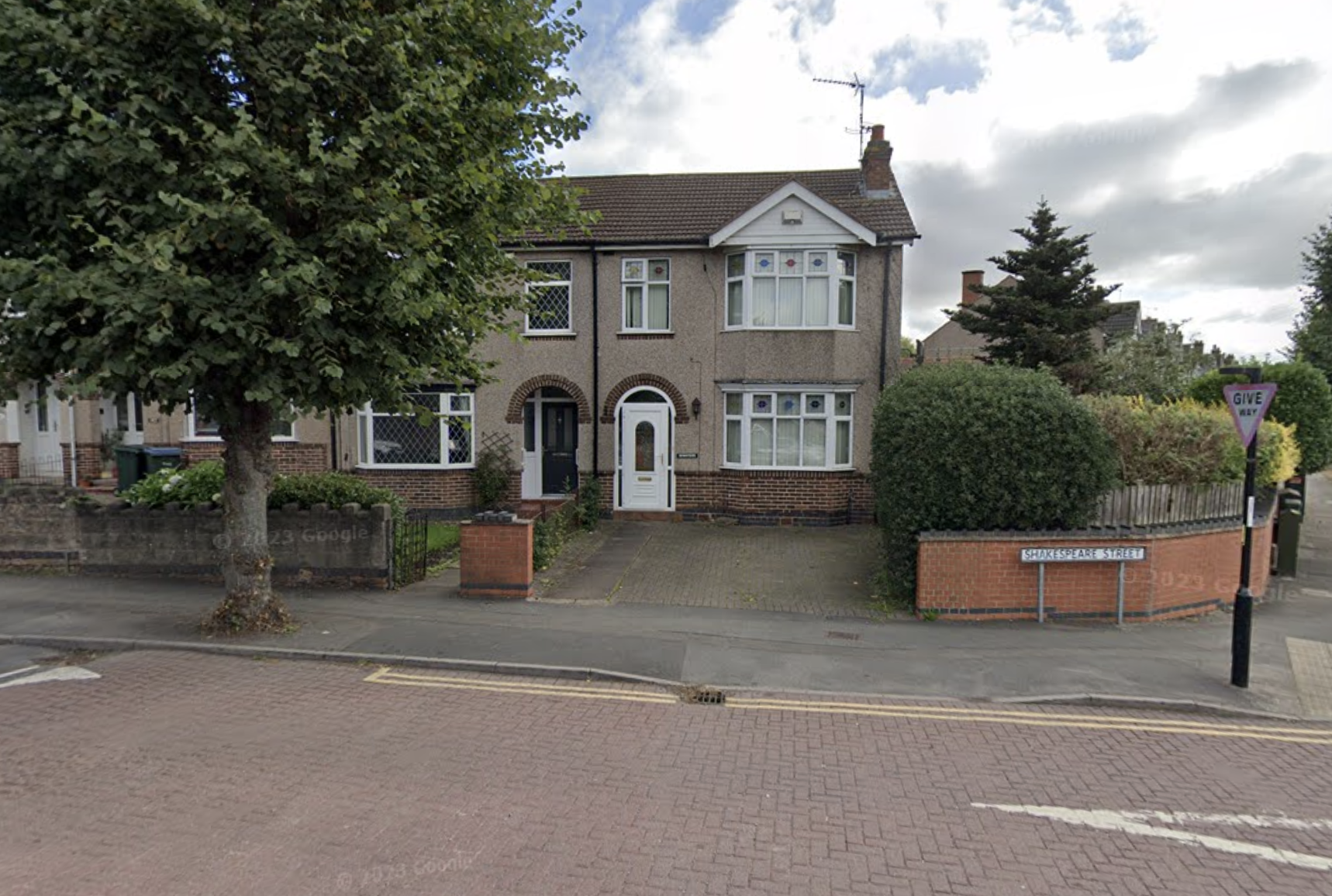 A street view of Shakespeare Street in Stoke, Coventry, showing residential houses, hedges, and a street sign.