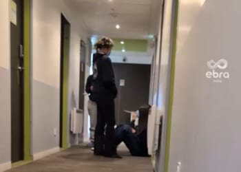 Students from a British private school are among nearly two hundred youngsters hit by 'severe' food poisoning at a French ski resort. Pictured: Children with facemasks sit in a hallway inside the holiday centre where scores of students have fallen in