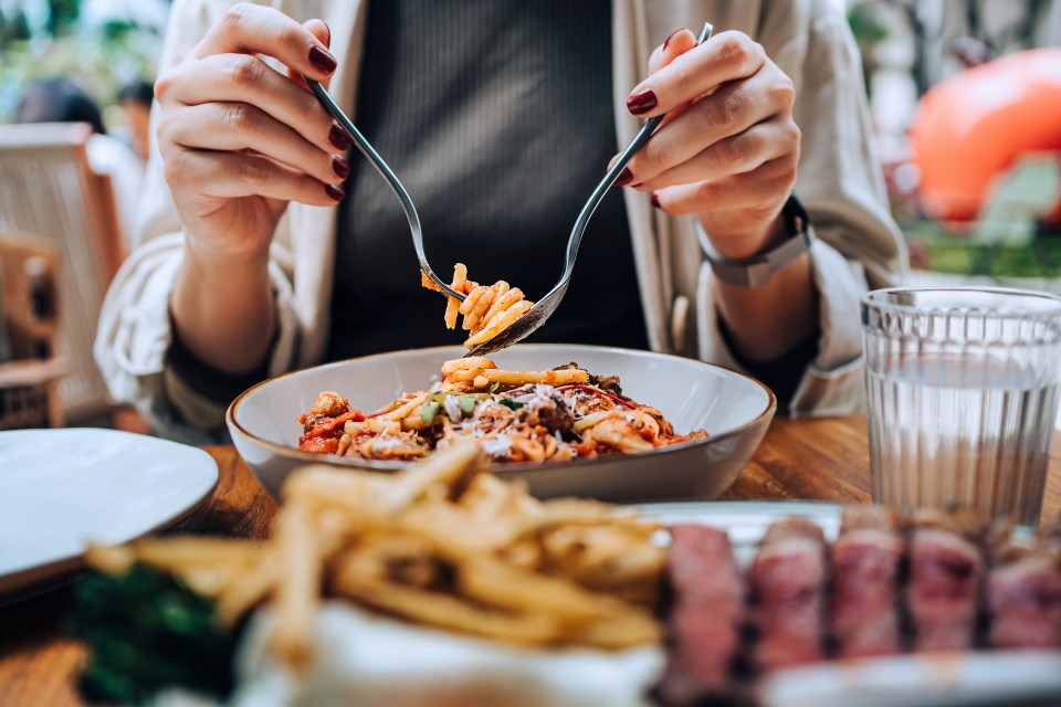 Close-up of a person twirling spaghetti bolognese with a fork and spoon.