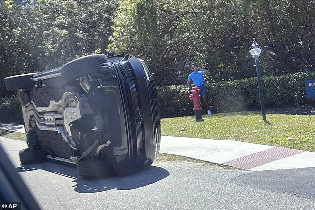 Golfer Tiger Woods, 50, stands by his overturned vehicle in Jupiter Island, Florida