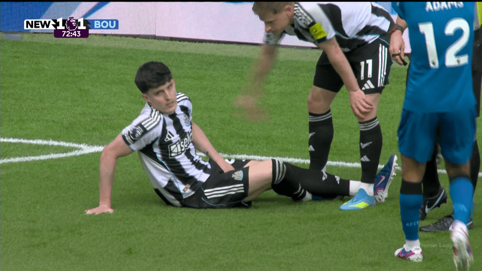 A football player sits on the field as another player leans over him, with the score NEW 1-1 BOU shown at the top of the screen.