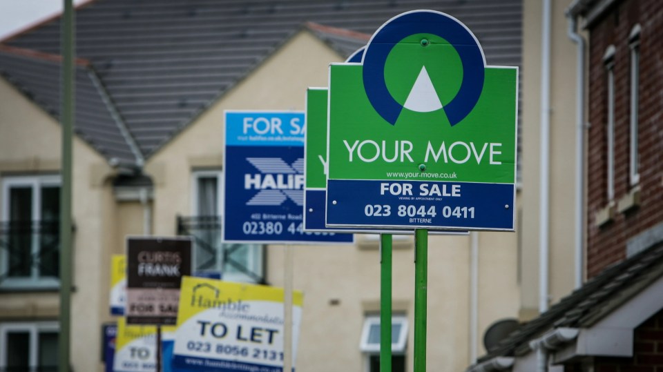 "Your Move" real estate sign outside a residential house, with other real estate signs blurred in the background.