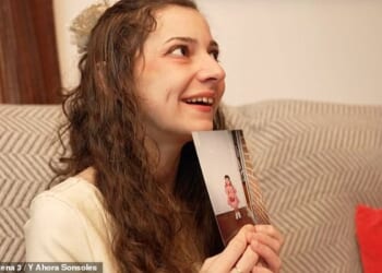 Noelia smiles as she holds up a picture from her childhood taken before her life was marked by abuse and trauma