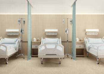 A hospital room with three beds and wooden decoration.