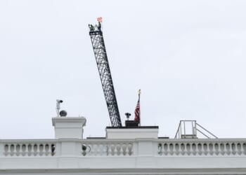 Workers are seen on top of a construction crane above the White House on April 28, 2026, in Washington, D.C.