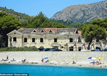 Beachgoers soak up the sun in front of abandoned Kupari resort's Grand Hotel