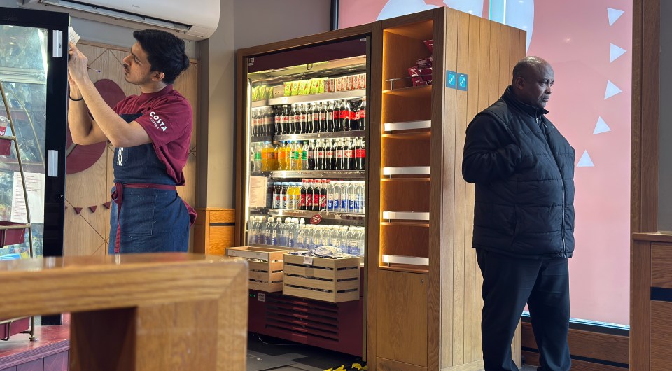 A Costa Coffee employee and a security guard inside a Costa Coffee shop.