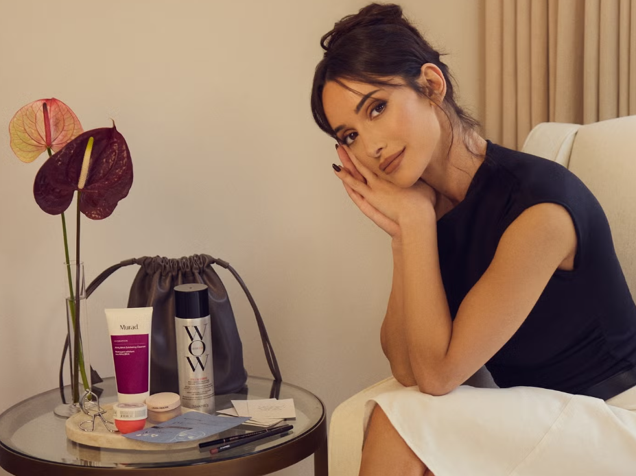 Roxie Nafousi sitting next to a table with beauty products, including Murad and Color Wow.