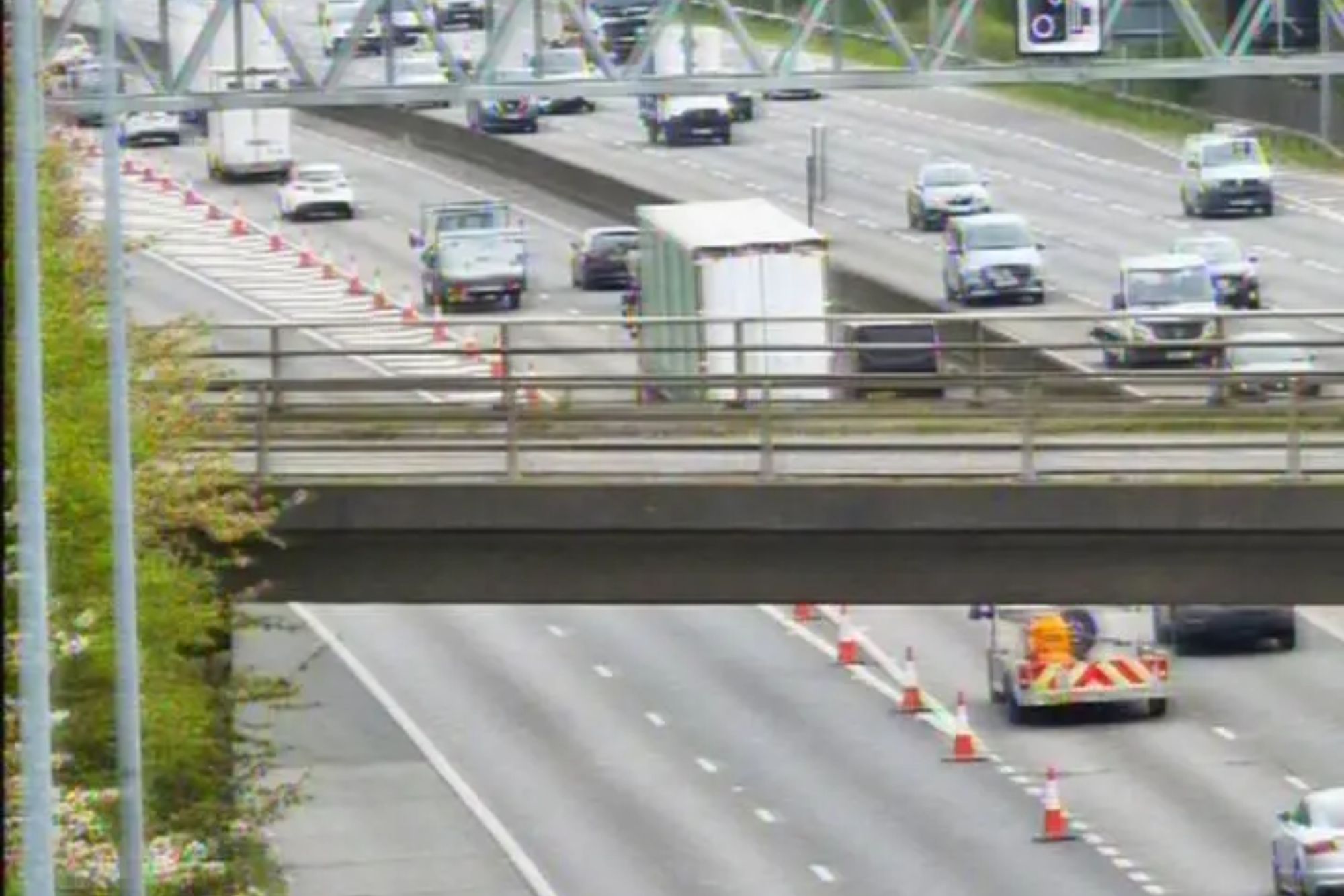 An image collage containing 1 images, Image 1 shows Cars driving on a multi-lane highway, with traffic cones in some lanes