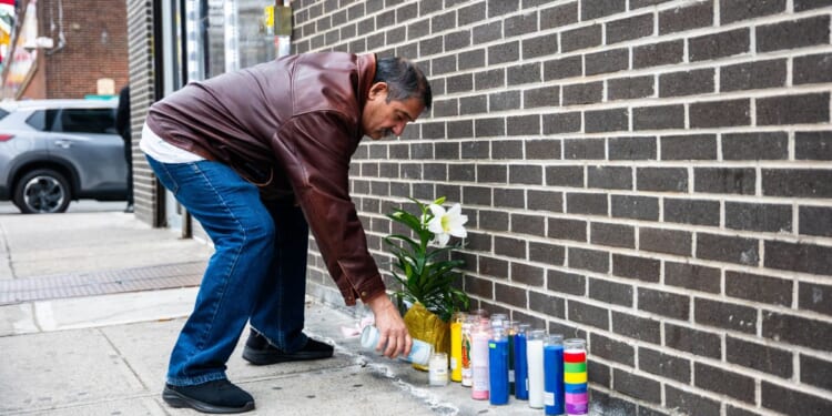 A man lights a candle at the corner where a 7-month-old baby was killed by a stray bullet while sitting in her stroller in Brooklyn Wednesday afternoon.