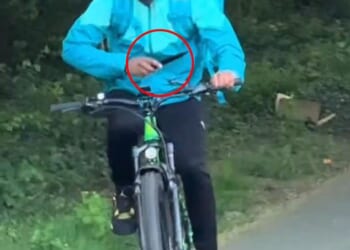 A man wearing a turquoise Deliveroo jacket and branded delivery bag is seen throwing the large knife into the bushes