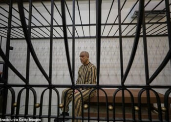 Atef Najib, wearing a striped prison uniform, sat seemingly emotionless on Sunday in a cage in a courtroom in Central Palace of Justice, in Syria's capital, Damascus