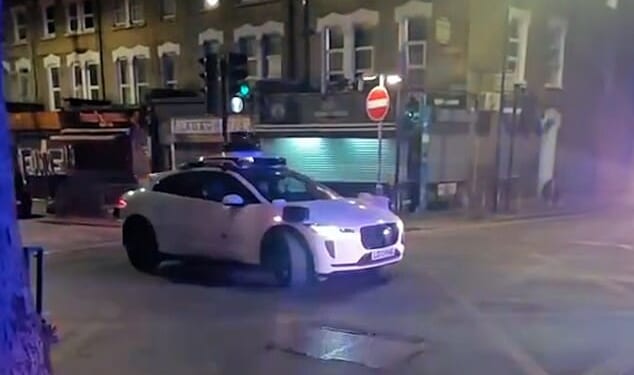 This is the moment a Waymo car drives straight into crime scene tape, narrowly avoiding a police vehicle before coming to a standstill