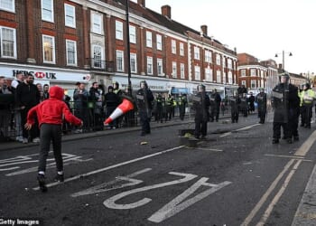 A traffic cone flying in the direction of armed police in Epsom on Wednesday evening as protests broke out in the upmarket Surrey town