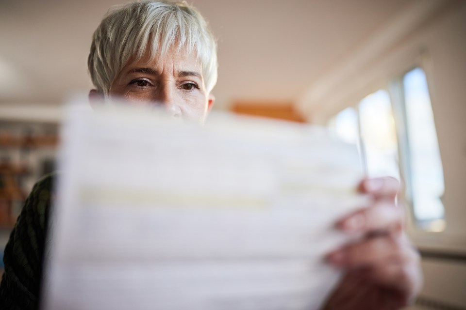 A senior woman examining financial documents at home.