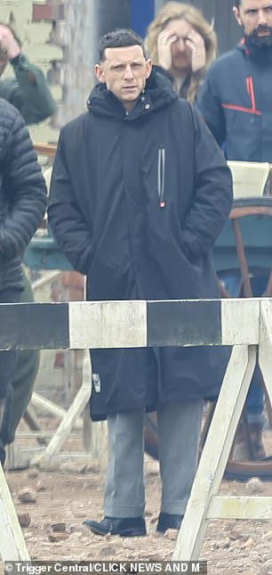 During a break in filming he wrapped in a padded black coat