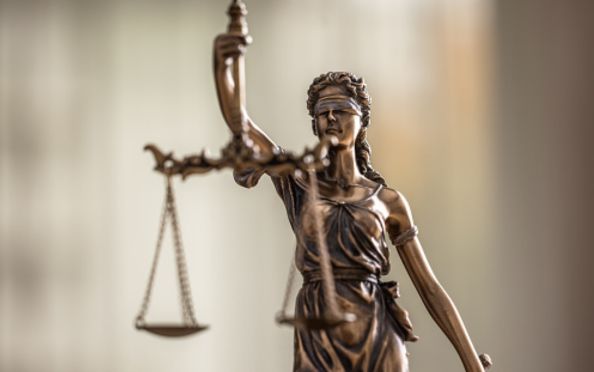 Lady Justice bronze statuette stands with the weight scales of Justice.