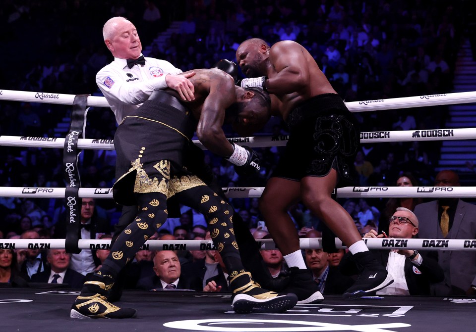 Referee Mark Bates pulling apart boxers Deontay Wilder and Derek Chisora during a heavyweight fight.