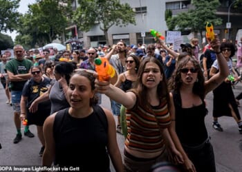 People are seen spraying tourists and buildings with water guns and pistols during an anti-tourism demonstration in Barcelona