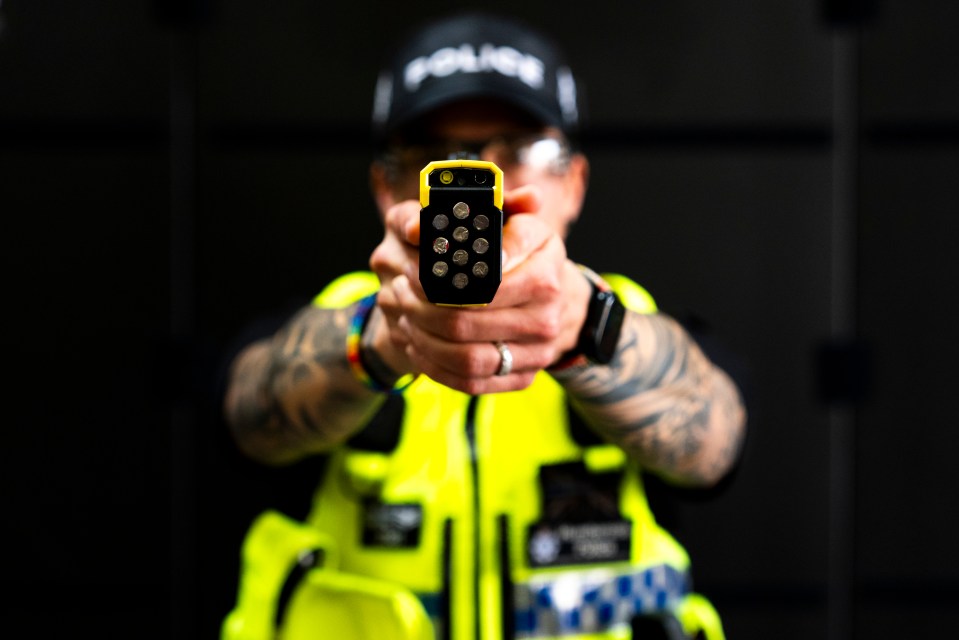 A police officer in a high-visibility vest aims a Taser 10 directly forward.