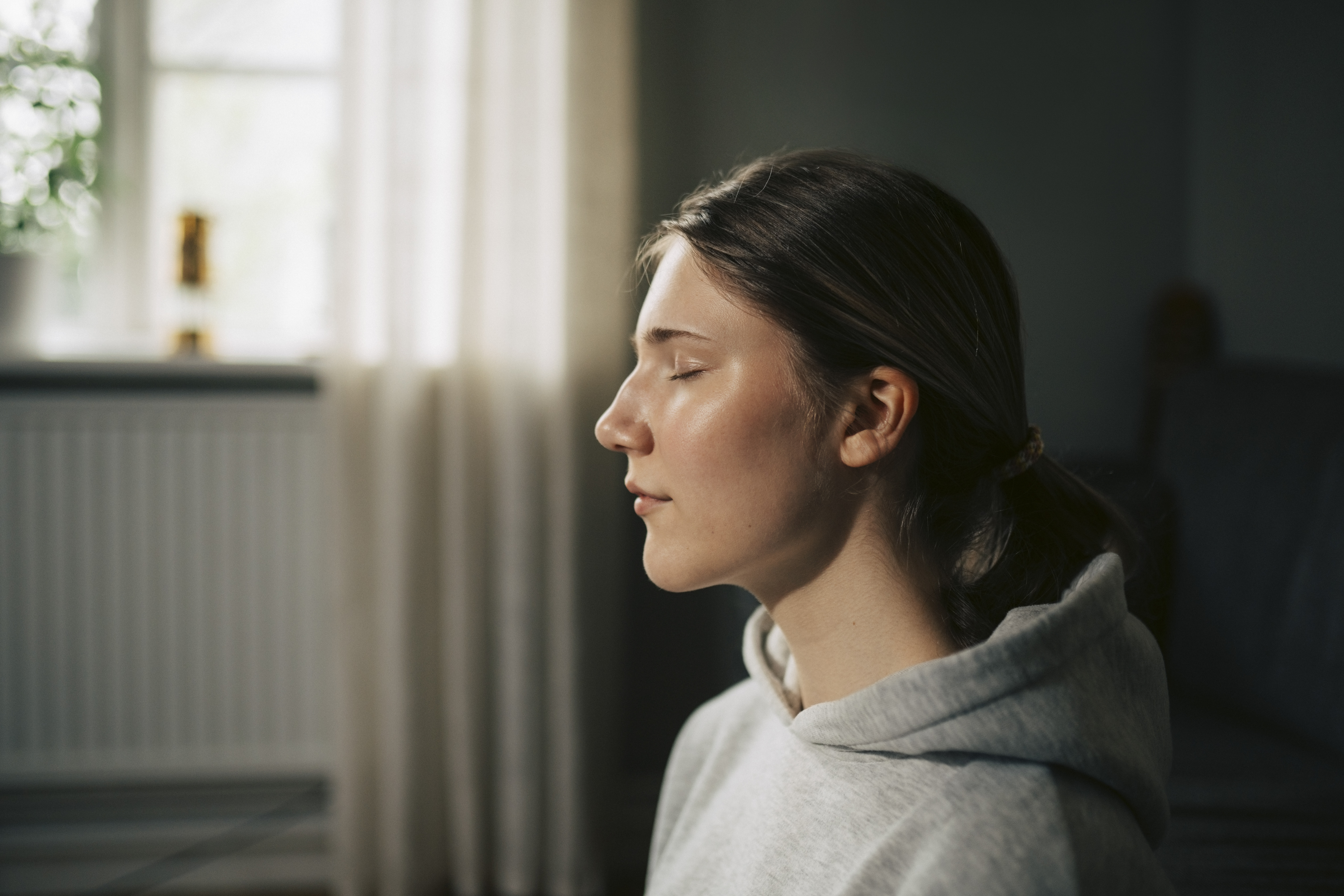 Young woman with eyes closed meditating at home.