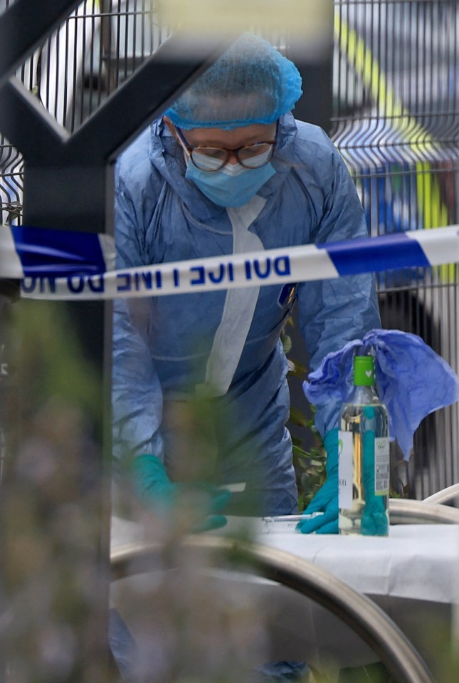 A police forensics officer in a blue hazmat suit, face mask, and hairnet works at the scene of an attempted arson attack at Finchley Reform Synagogue.