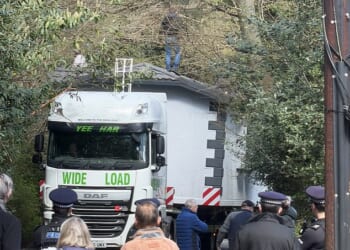 Confrontation: Locals in the Kent village look on as a truck carrying the travellers' home gets wedged in the Kent lane leading to the site