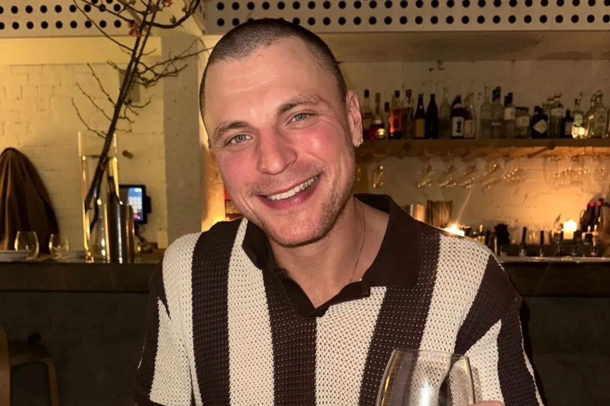 An image collage containing 1 images, Image 1 shows Konrad Bien-Stephen smiling while holding a glass of red wine at a restaurant