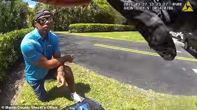 Woods kneels at the side of the road after rolling his SUV on a quaint Jupiter Island street