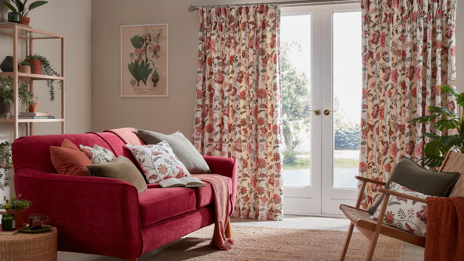 Living room with a red sofa, a wooden shelf with plants, and floral curtains.
