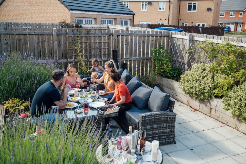Friends and family enjoying a barbecue in a garden.