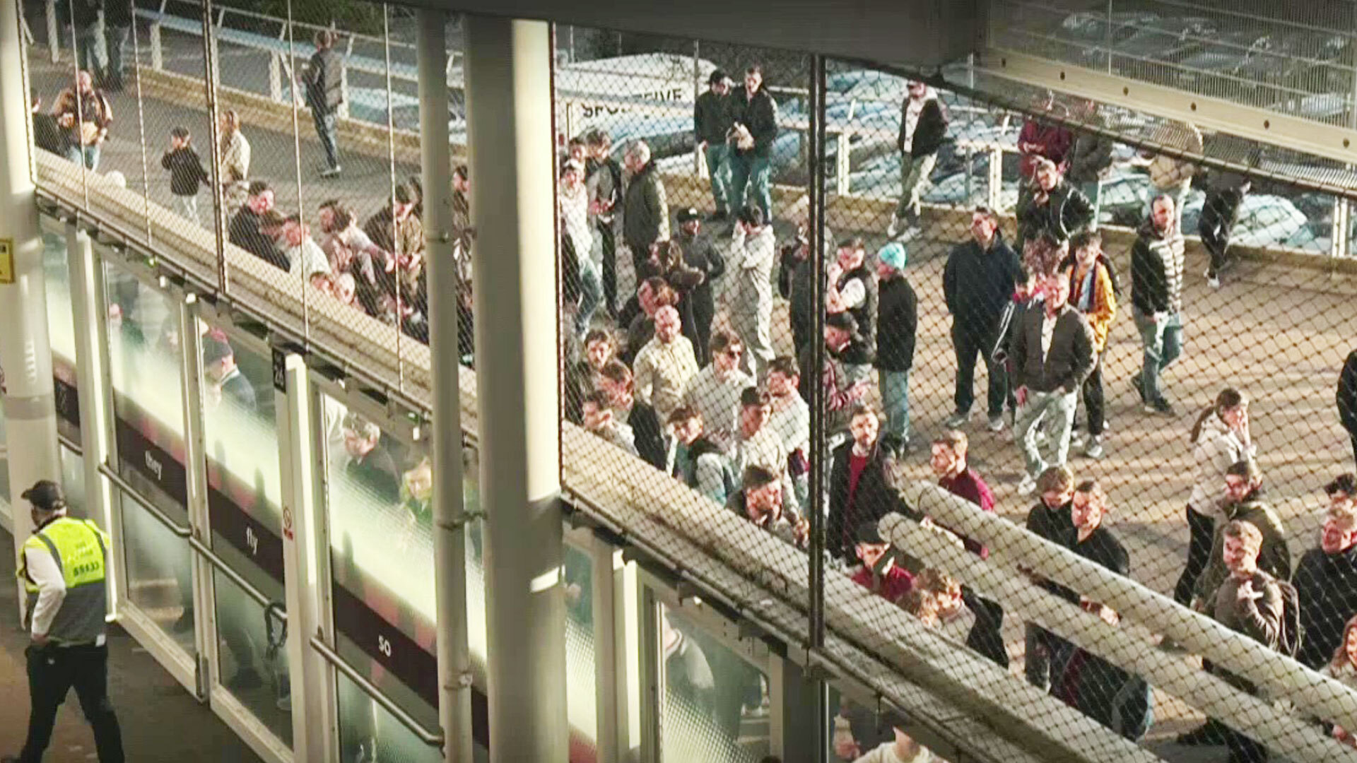 West Ham fans watching a soccer match from behind a safety net.