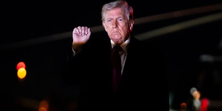 President Donald Trump holds up a fist as he exits Air Force One at Joint Air Base Andrews, Maryland, on March 29, 2026.