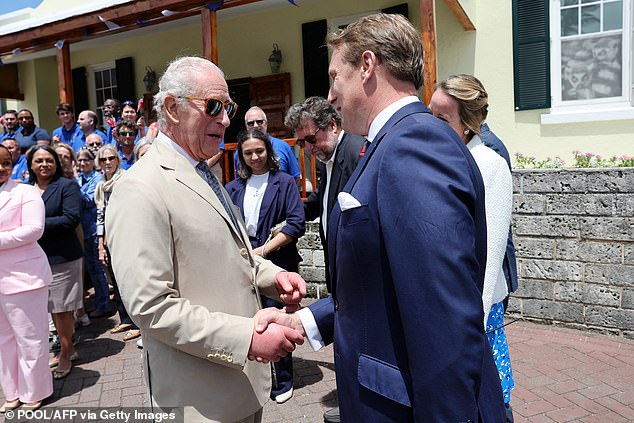 Charles shake hands with former assistant equerry James Larner during a visit to the Bermuda Aquarium Museum