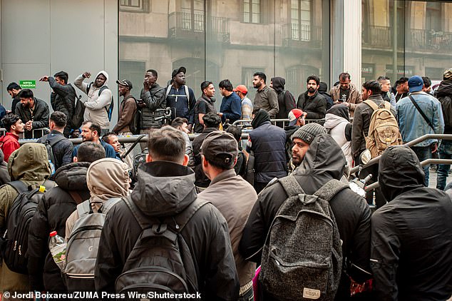 Migrants line up in the Gothic Quarter of Barcelona as they seek assistance with migrant regularisation documents and procedures promoted by the Spanish government
