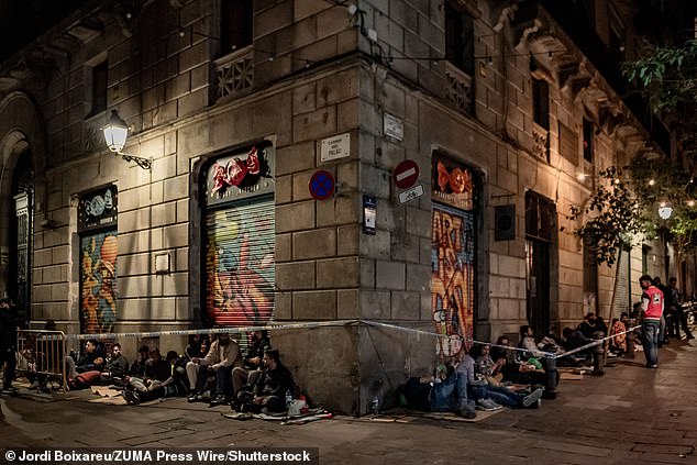 People wait overnight in line in Barcelona's Gothic Quarter ahead of the opening of citizen service offices, seeking assistance with migrant regularisation procedures