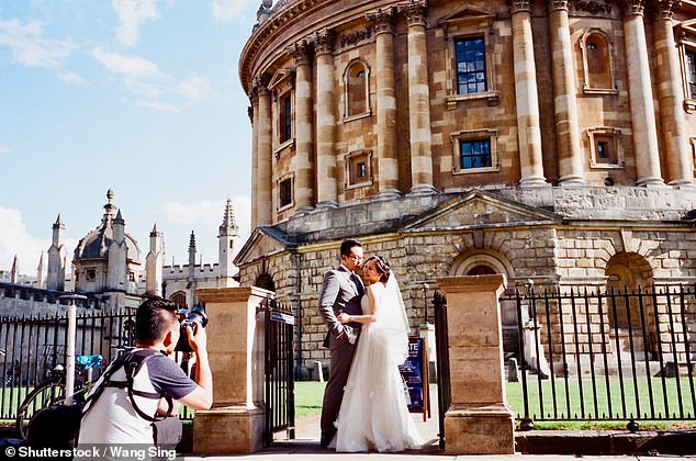 A newly-married couple being photographed outside the Radcliffe Camera in Oxford